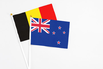 New Zealand and Belgium stick flags on white background. High quality fabric, miniature national flag. Peaceful global concept.White floor for copy space.