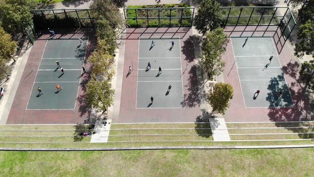 Aerial view of three volleyball courts with young people playing, drone slowly descending.