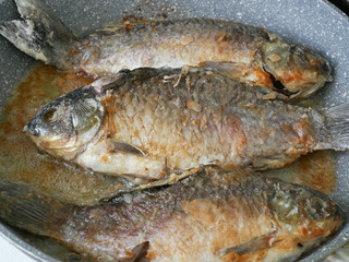 Three crucian fish are fried on a pan