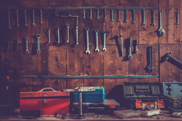 Workshop scene. Old tools hanging on wall in workshop, Tool shelf against a table and wall, vintage...