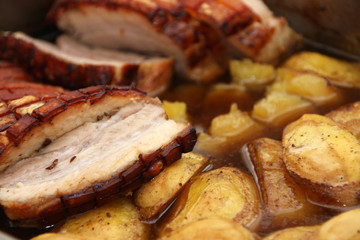 Homemade roast pork belly with fried potatoes sliced ​​in juice close up