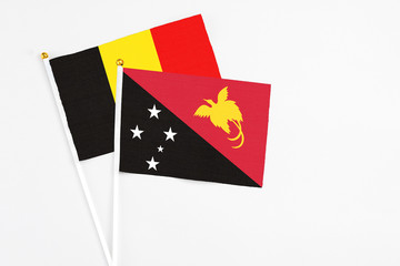 Papua New Guinea and Belgium stick flags on white background. High quality fabric, miniature national flag. Peaceful global concept.White floor for copy space.