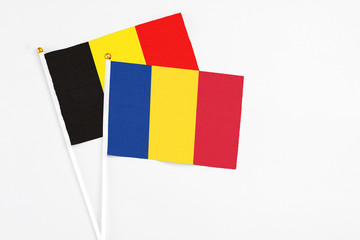 Romania and Belgium stick flags on white background. High quality fabric, miniature national flag. Peaceful global concept.White floor for copy space.