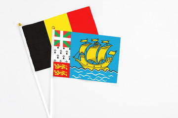 Saint Pierre And Miquelon and Belgium stick flags on white background. High quality fabric, miniature national flag. Peaceful global concept.White floor for copy space.