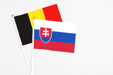 Slovakia and Belgium stick flags on white background. High quality fabric, miniature national flag. Peaceful global concept.White floor for copy space.