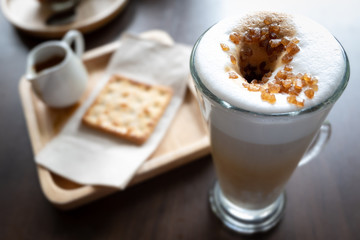 Top view of Hot cappuccino coffee brown sugar toppingand cracker on table background, vintage style. Close up shot.