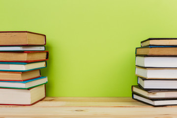 Simple composition of many hardback books, raw of books on wooden table and light green background