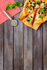 Pizza with tomato, basil, olives, cheese on dark wooden background top view copy space