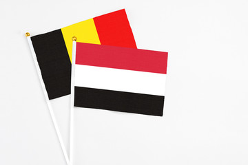 Yemen and Belgium stick flags on white background. High quality fabric, miniature national flag. Peaceful global concept.White floor for copy space.