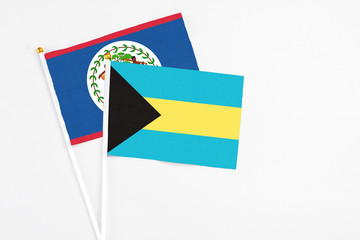 Bahamas and Belize stick flags on white background. High quality fabric, miniature national flag. Peaceful global concept.White floor for copy space.