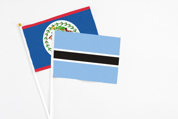 Botswana and Belize stick flags on white background. High quality fabric, miniature national flag. Peaceful global concept.White floor for copy space.