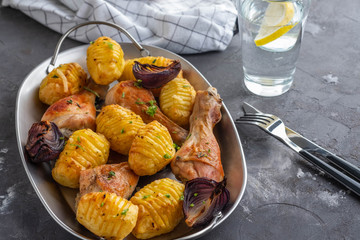 Roasted chicken leg with potatoes cumin and garlic on black background. Copy space.