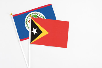 East Timor and Belize stick flags on white background. High quality fabric, miniature national flag. Peaceful global concept.White floor for copy space.