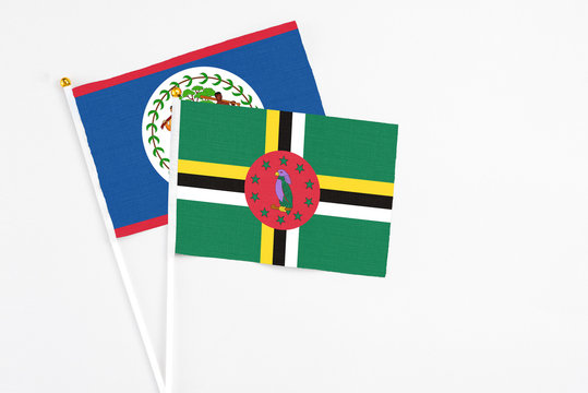 Dominica and Belize stick flags on white background. High quality fabric, miniature national flag. Peaceful global concept.White floor for copy space.