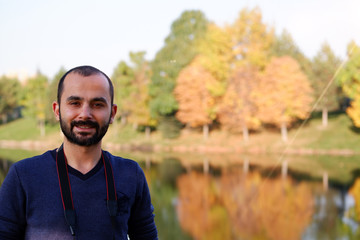  portrait of smiling young man with beautiful autumn background and reflection