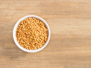 Fenugreek in white bowl on a brown wooden background. Indian cuisine, ayurveda, naturopathy, modern apothecary concept