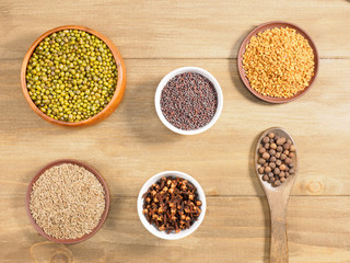 Allspice, mung bean, mustard seeds, fenugreek, cumin, cloves on brown wooden background. Indian cuisine, ayurveda, naturopathy, modern apothecary concept