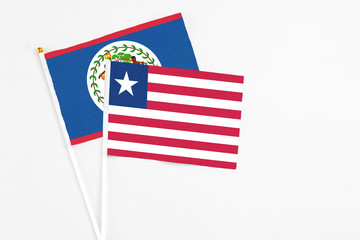 Liberia and Belize stick flags on white background. High quality fabric, miniature national flag. Peaceful global concept.White floor for copy space.