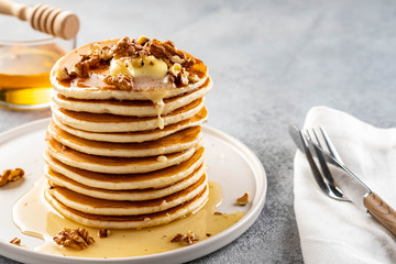 Tasty breakfast. Homemade pancakes with crushed walnut, honey or maple syrup on grey background.