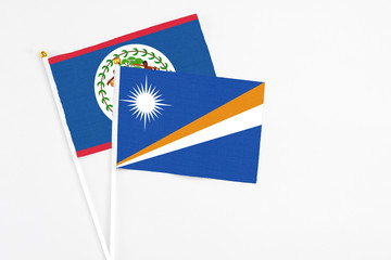 Marshall Islands and Belize stick flags on white background. High quality fabric, miniature national flag. Peaceful global concept.White floor for copy space.