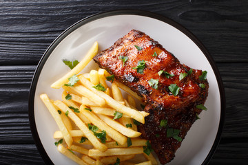 Delicious barbecue spicy short ribs with french fries close-up on a plate. Horizontal top view