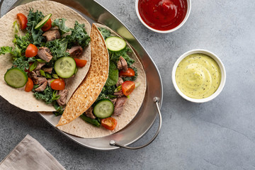 Two mexican pork carnitas tacos with sauces and vegetables.