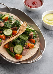 Two mexican pork carnitas tacos with sauces and vegetables.