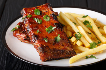 Sticky short ribs with french fries close-up on a plate. horizontal