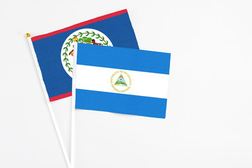 Nicaragua and Belize stick flags on white background. High quality fabric, miniature national flag. Peaceful global concept.White floor for copy space.