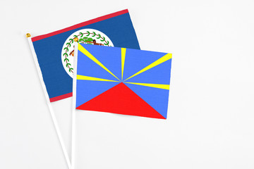 Reunion and Belize stick flags on white background. High quality fabric, miniature national flag. Peaceful global concept.White floor for copy space.