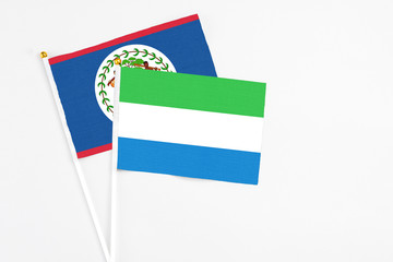 Sierra Leone and Belize stick flags on white background. High quality fabric, miniature national flag. Peaceful global concept.White floor for copy space.