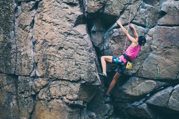 The girl climbs the granite rock.