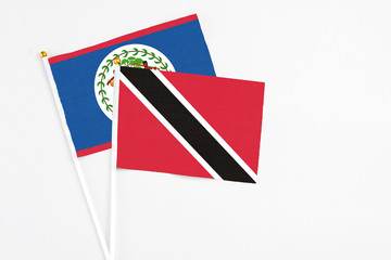 Trinidad And Tobago and Belize stick flags on white background. High quality fabric, miniature national flag. Peaceful global concept.White floor for copy space.