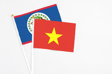 Vietnam and Belize stick flags on white background. High quality fabric, miniature national flag. Peaceful global concept.White floor for copy space.