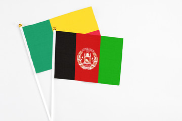 Afghanistan and Benin stick flags on white background. High quality fabric, miniature national flag. Peaceful global concept.White floor for copy space.