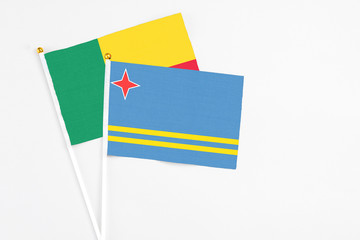 Aruba and Benin stick flags on white background. High quality fabric, miniature national flag. Peaceful global concept.White floor for copy space.