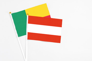 Austria and Benin stick flags on white background. High quality fabric, miniature national flag. Peaceful global concept.White floor for copy space.