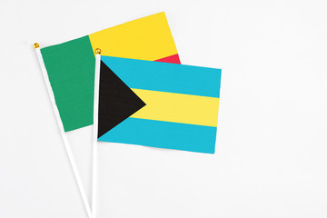 Bahamas and Benin stick flags on white background. High quality fabric, miniature national flag. Peaceful global concept.White floor for copy space.