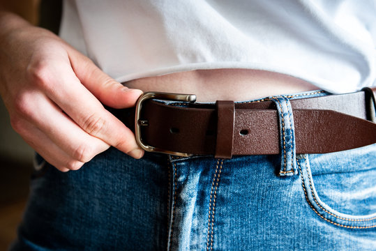 Woman wear leather belt on blue jeans.