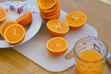 Fresh citrus orange halves on the plate and cuttimg board after making orange juice at home