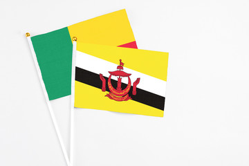 Brunei and Benin stick flags on white background. High quality fabric, miniature national flag....