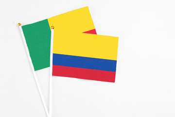 Colombia and Benin stick flags on white background. High quality fabric, miniature national flag. Peaceful global concept.White floor for copy space.