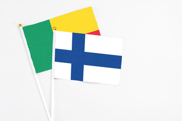 Finland and Benin stick flags on white background. High quality fabric, miniature national flag. Peaceful global concept.White floor for copy space.