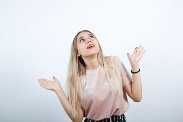 Portrait of happy joyful young woman in casual clothes looking up, rising hands, isolated on white background. People sincere emotions, lifestyle concept