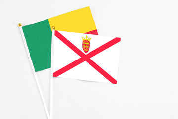 Jersey and Benin stick flags on white background. High quality fabric, miniature national flag. Peaceful global concept.White floor for copy space.