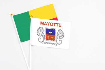 Mayotte and Benin stick flags on white background. High quality fabric, miniature national flag. Peaceful global concept.White floor for copy space.
