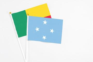 Micronesia and Benin stick flags on white background. High quality fabric, miniature national flag. Peaceful global concept.White floor for copy space.