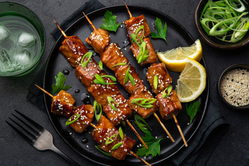 Teriyaki salmon skewers on black plate