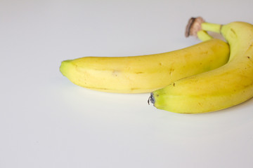 ripe yellow banana on white background. two bananas are on the table. space for text. the view from the top.
