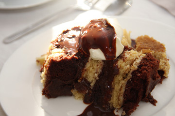 Traditional Hungarian sweet dessert with whipped cream and chocolate sauce called somloi galuska on a white plate on a set table